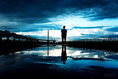 Reflection of man in water at dusk