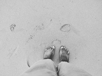 Low section of man standing on sand at beach