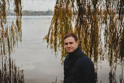 Portrait of handsome man standing against lake