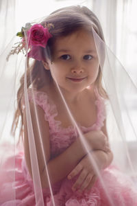 Portrait of a girl in a pink dress and a flower with a rose in her head in the studio