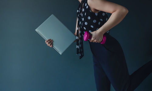 Woman holding umbrella standing against wall