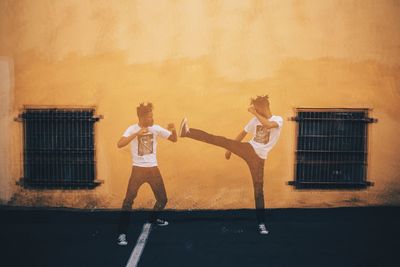 Double exposure of man fighting self against yellow building