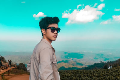 Young man wearing sunglasses standing against sky