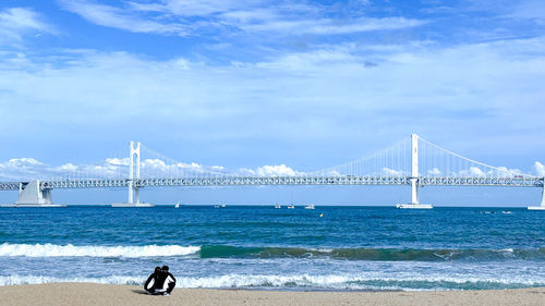 Rear view of woman standing on beach against sky