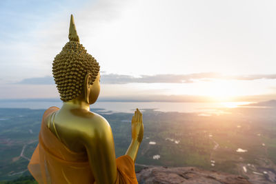 Buddha statue with sunrise and pa sak jolasid dam at khao phra ya dern thong view point. 