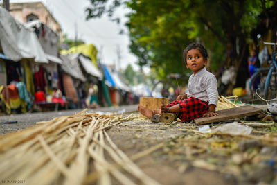 Full length of child sitting at roadside