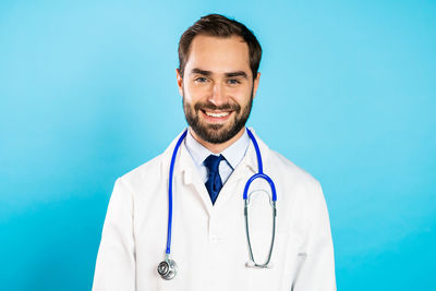 Portrait of smiling young man against blue background