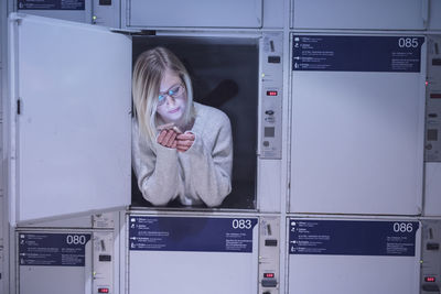 Young woman using phone in locker