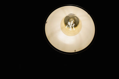 Low angle view of illuminated light bulb against black background