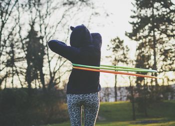 Rear view of woman with hula hoop in park against clear sky