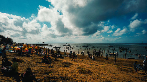 Group of people on beach against sky