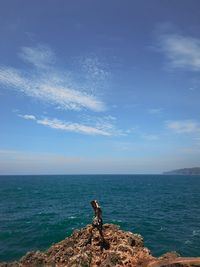 Man standing on rocks by sea against sky