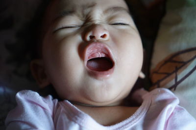 Close-up of cute baby girl with open mouth on bed