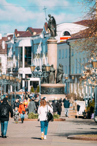 Rear view of people walking on street in city