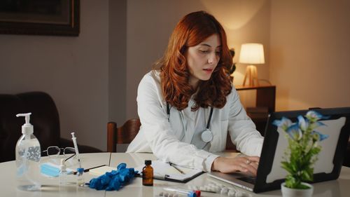 Young beautiful italian female doctor writes the prescription on the laptop