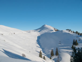 Scenic view of snow covered mountains against clear blue sky