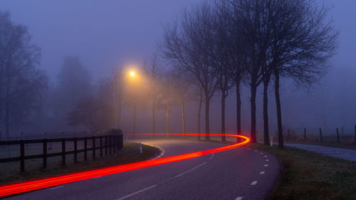 Rear view of man walking on road against sky at night