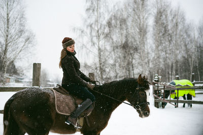 Beautiful woman riding horse on snow covered field