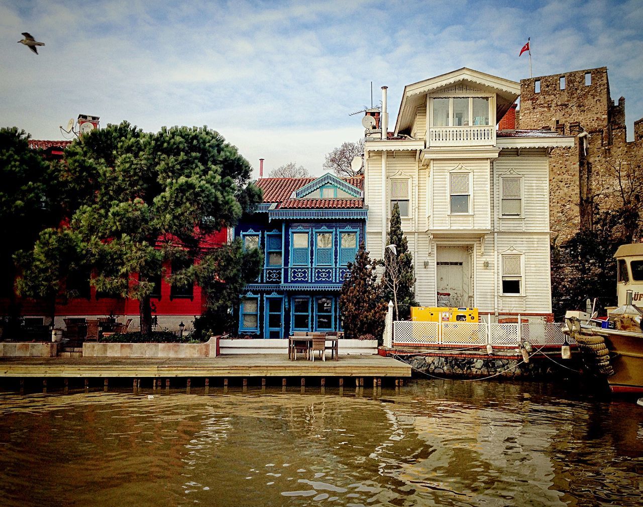 architecture, building exterior, built structure, water, waterfront, sky, house, bird, residential building, residential structure, cloud - sky, tree, building, river, incidental people, day, city, cloud, canal, outdoors