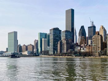 Sea by modern buildings against sky in city