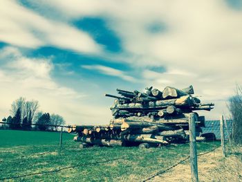 Stack of logs on field against sky