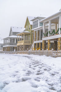 Snow covered houses by buildings against clear sky