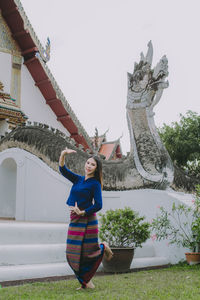 Young woman standing by sculpture against plants