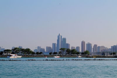 Sea by buildings against clear sky