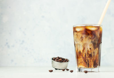 Iced coffee with milk in a tall glass with roasted coffee beans. summer refreshment drink. 