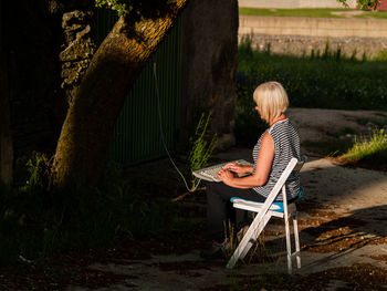 Boy sitting on chair against plants
