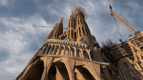 Low angle view of cranes at sagrada familia against sky