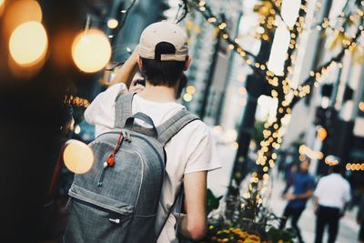 Rear view of woman walking on illuminated christmas tree at night