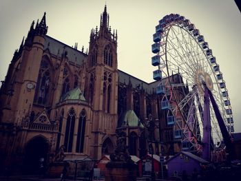 Low angle view of ferris wheel against buildings