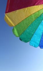 Low angle view of multi colored flag against clear blue sky