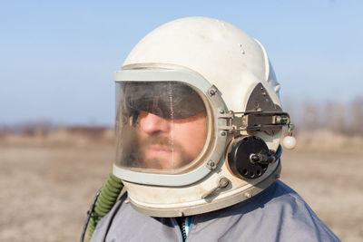 Close-up of man wearing helmet on field against sky