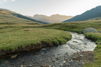 Scenic view of stream by mountains against sky