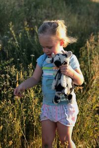 Cute girl holding plant and toy on field