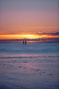 Silhouette people on beach against sky during sunset