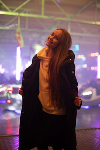 Woman standing against illuminated light at night