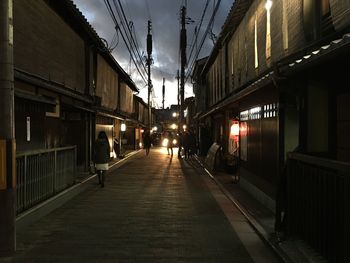 Illuminated railroad tracks in city against sky at night