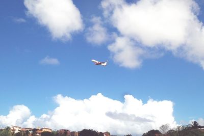 Low angle view of airplane flying against cloudy sky