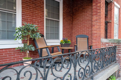 Two rocking chairs sitting on a porch with an iron railing in the city.