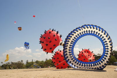 Low angle view of multi colored balloons on beach against sky