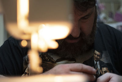 Man looking down while sitting with equipment in workshop