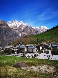 Houses on field by mountain against sky