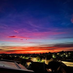 Scenic view of illuminated city against sky at sunset