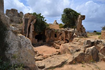 Ruins of rock formations against cloudy sky