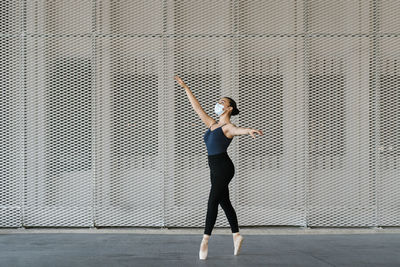 Female ballet dancer standing on tiptoe while practicing against metal wall