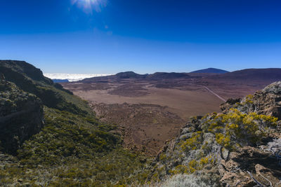 Scenic view of landscape and mountains against blue sky