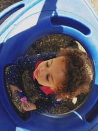 Directly above shot of girl amidst blue baby walker at playground